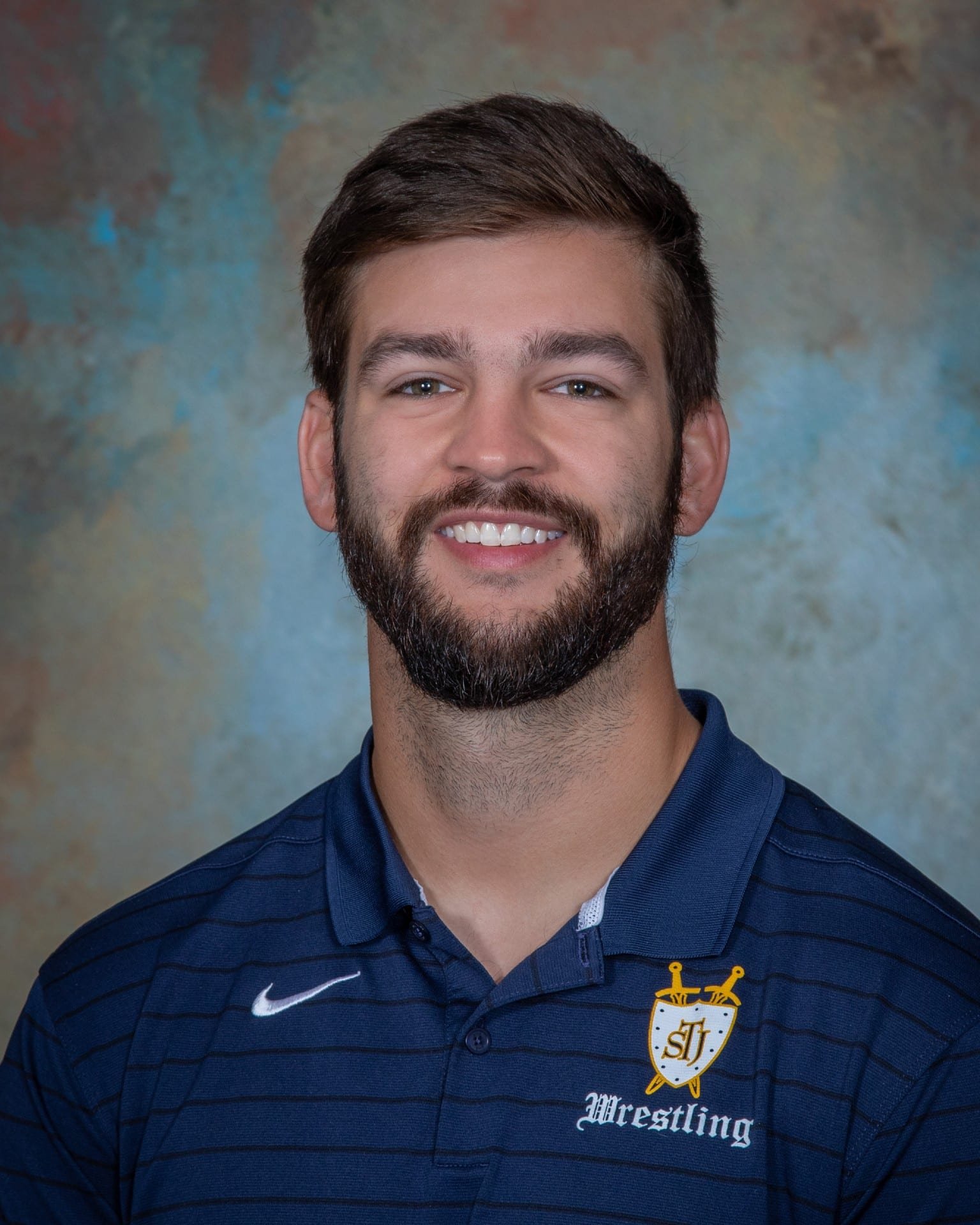 a man wearing a blue shirt and smiling at the camera